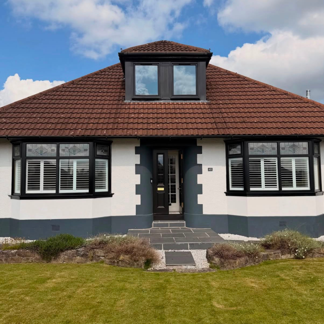 White rendered bungalow with resprayed jet black bay windows and front door.